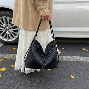 Detail of black pleated soft leather bag with silver metal buckle and cross strap design