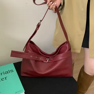 Detail of dark red hobo bag featuring decorative belt buckles and metallic eyelets