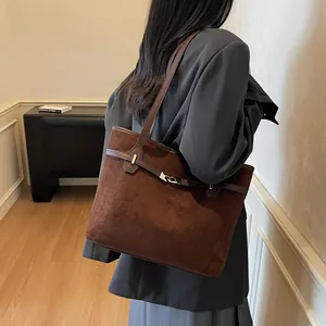 Détail macro du sac cabas en daim marron foncé avec lanières en cuir et boucle en métal