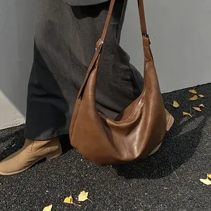 Vue détaillée d'un sac demi-lune vintage en cuir marron foncé avec texture plissée douce