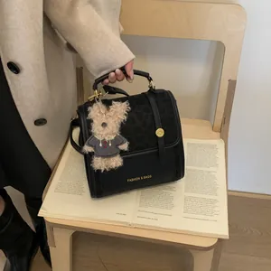Détail du sac à main noir avec rabat imprimé léopard et breloque ours en peluche
