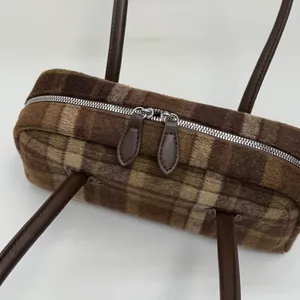 Détail du sac à main en peluche à carreaux marron avec double fermeture éclair et cuir