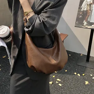 Photo de style urbain d'un grand sac hobo marron en simili cuir souple porté à l'épaule