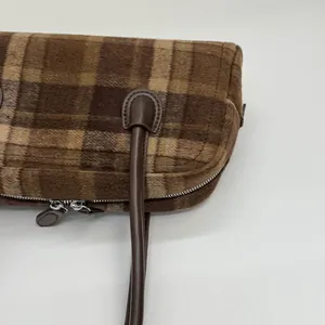 Détail d'un sac à main en peluche à carreaux marron avec fermeture éclair et cuir