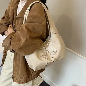Detail of off-white hobo bag with silver star-shaped metal rivets on shoulder strap