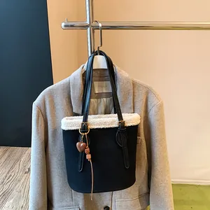 Detail einer schwarzen Wildleder-Beuteltasche mit Pelzbesatz und Herz-Anhänger-Dekor