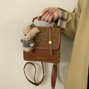 Détail d'un sac à dos marron patchwork avec rabat léopard et breloque ours en peluche