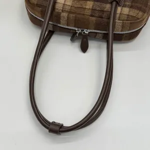 Détail du sac cabas en peluche à carreaux marron avec double fermeture éclair argentée