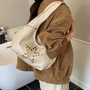 Detail view of cream-white hobo bag with star-shaped metal studs and aged PU leather texture