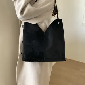 Détail d'un grand sac cabas en daim noir avec coupe en V sur un manteau blanc élégant