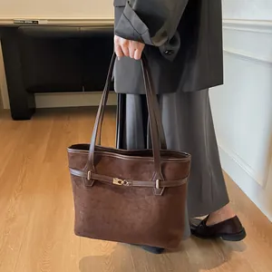 Détail du sac cabas marron en daim avec une boucle dorée élégante et une texture fine