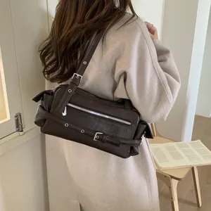 Model wearing dark brown vintage leather baguette bag with silver buckles and zippers