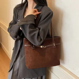 Détail du sac cabas en daim marron foncé avec fermoir tournant métallique et lanière en cuir