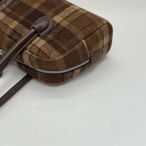 Détail de la texture du tissu écossais marron et des coutures de la poignée du sac