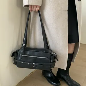 Detailed view of black motorcycle-style underarm bag worn with a white coat