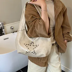 Detail of cream hobo bag featuring silver metal rivets in a star pattern