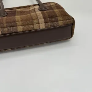 Vue macro détaillée de la texture du tissu écossais marron et de la base en cuir du sac