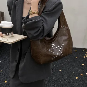 Detail of dark brown leather underarm bag with silver stud star pattern on model