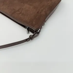 Detailaufnahme der dunkelbraunen Wildledertasche mit Silberreißverschluss und Lederriemen