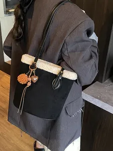 Schwarze Wildleder-Beuteltasche mit weißem Pelzbesatz und Herzanhänger am Modell