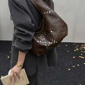 Detail of dark brown leather hobo bag featuring silver star studs and wide shoulder strap