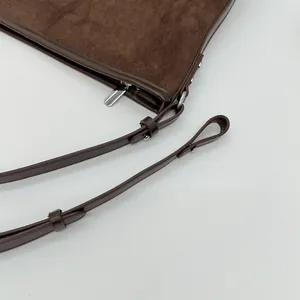 Detailaufnahme der dunkelbraunen Wildleder-Beuteltasche mit Silberschnalle und Reißverschluss