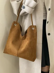 Sac cabas en cuir mat marron porté par un mannequin dans un style élégant et minimaliste