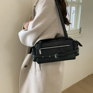 On-body view of a black vintage moto-style underarm bag with silver buckle and eyelet details