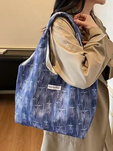 Deep blue tote bag with white star pattern worn over the shoulder by a model in a trench coat