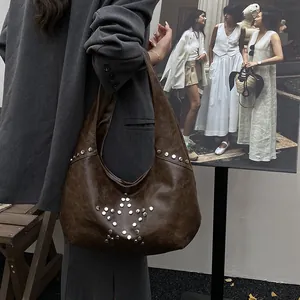 Detail of dark brown hobo bag with star-shaped silver studs shown on a model