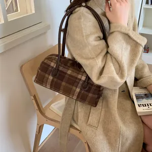 Détail d'un sac à main en laine à carreaux marron porté par un mannequin en manteau
