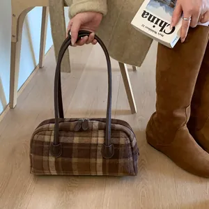 Détail d'un sac Boston à carreaux vintage avec de longues anses en cuir en hiver