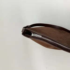 Detail der Wildleder-Beuteltasche mit Glattlederbesatz und silbernem Metallreißverschluss