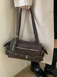 Retro dark brown motorcycle shoulder bag with silver hardware on a model in a beige coat