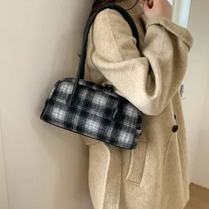 Détail d'un sac à main en tweed à carreaux noir et blanc avec anses en cuir longues