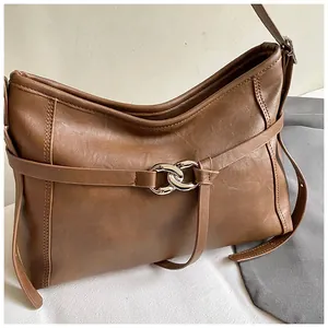 Détail du sac rétro marron avec un anneau métallique argenté et une texture en cuir fin