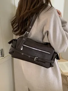 Retro motorcycle style dark brown shoulder bag with silver hardware on a model
