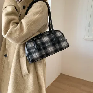 Sac Boston classique à carreaux noir et blanc porté avec un manteau d'hiver beige élégant