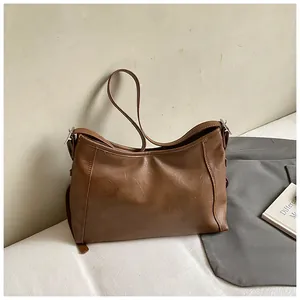 Détail du cabas vintage en cuir marron avec boucles en métal argenté et fine bandoulière
