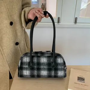 Détail du motif à carreaux et des fermetures éclair argentées sur un sac à main Boston