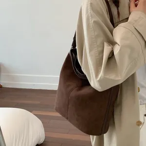Detail der dunkelbraunen Wildleder-Beuteltasche getragen zu einem beigen Trenchcoat