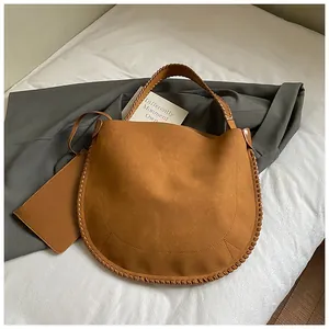 Vue détaillée du sac fourre-tout en daim marron avec bords tressés et mini pochette assortie