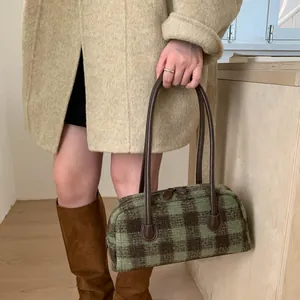 Détail du sac à main à carreaux avec tissu vert et marron et lanières en cuir