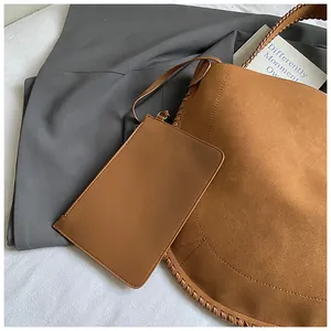 Gros plan d'un cabas en daim marron avec bords tressés et sa pochette assortie
