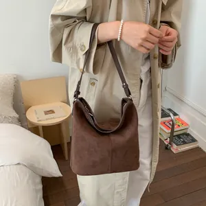 Detail der dunkelbraunen Wildleder-Beuteltasche kombiniert mit beige Trenchcoat