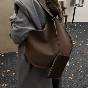 Détail du sac cabas en daim marron foncé avec bords tressés et une pochette amovible