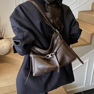 Détail du sac cabas vintage en cuir marron avec texture brillante et boucle métallique