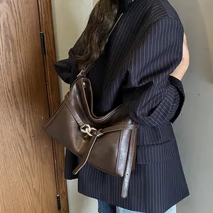 Détail du sac cabas rétro en cuir marron foncé avec anneau métallique et lanière latérale