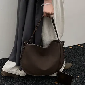 Détail du sac cabas marron foncé avec surpiqûres tressées et profil latéral porté par un mannequin
