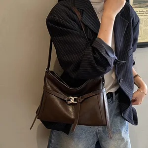 Détail du sac à bandoulière en cuir marron foncé avec boucle dorée et sangle